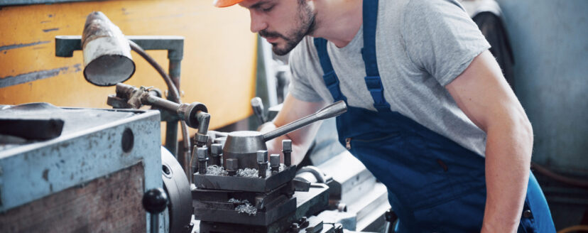 Portrait of a young worker in a hard hat at a large waste recycling factory. The engineer monitors the work of machines and other equipment.